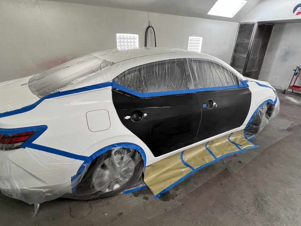 Sedan masked for paint around a replaced black door